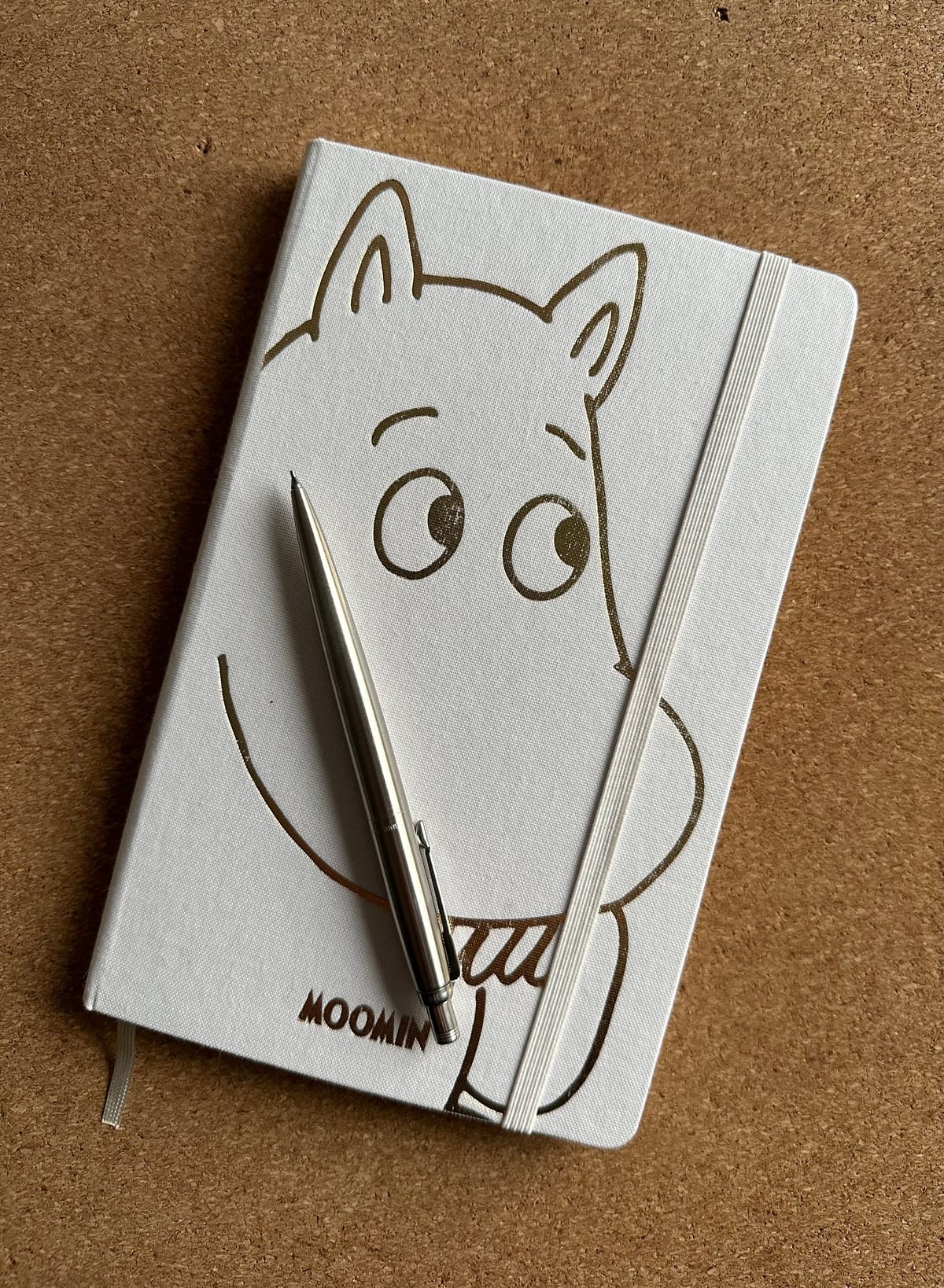 A white notebook with a gold embossed Moomin