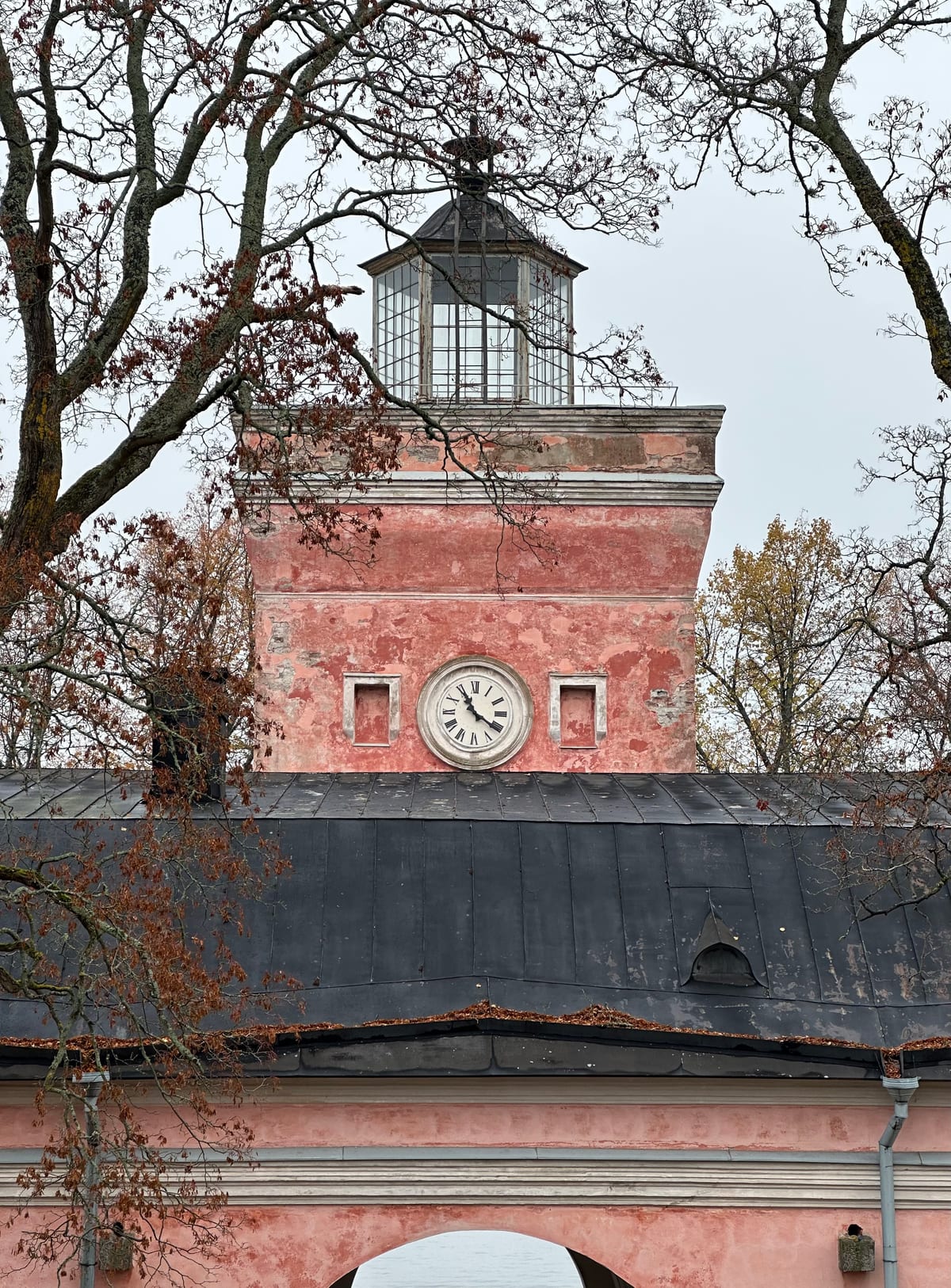 A pinkish-red tower of a building with a clock in it