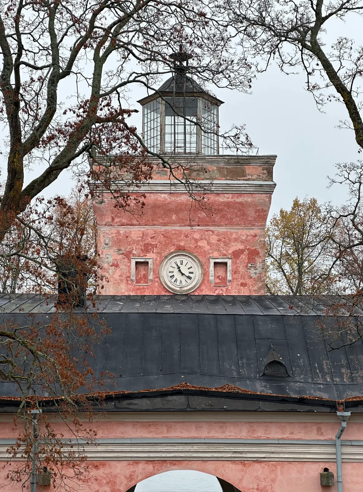 A pinkish-red tower of a building with a clock in it