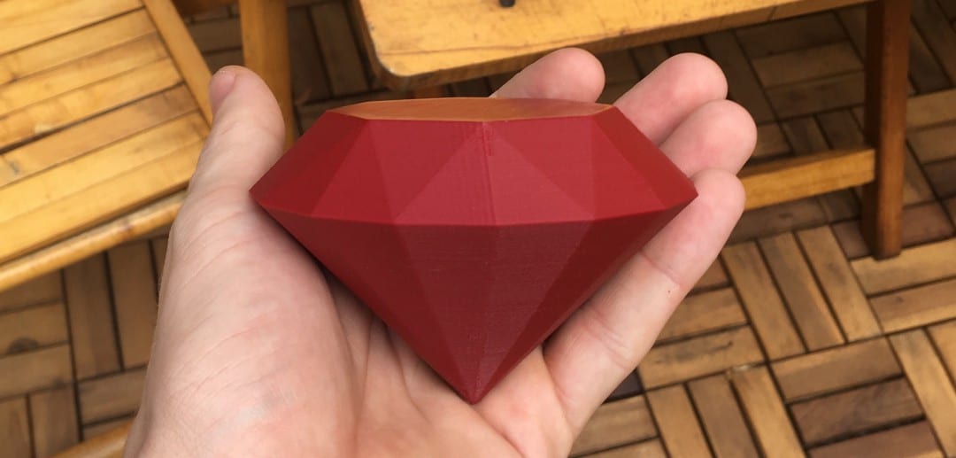 Hand holding a plastic Ruby gemstone